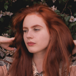 Redhead woman in front of flower bush